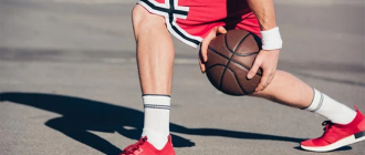 Баскетболист переводит мяч под ногой, делает финт